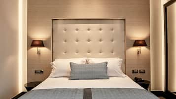 A neatly made bed with a tufted headboard, two bedside lamps, and a small table with a telephone.