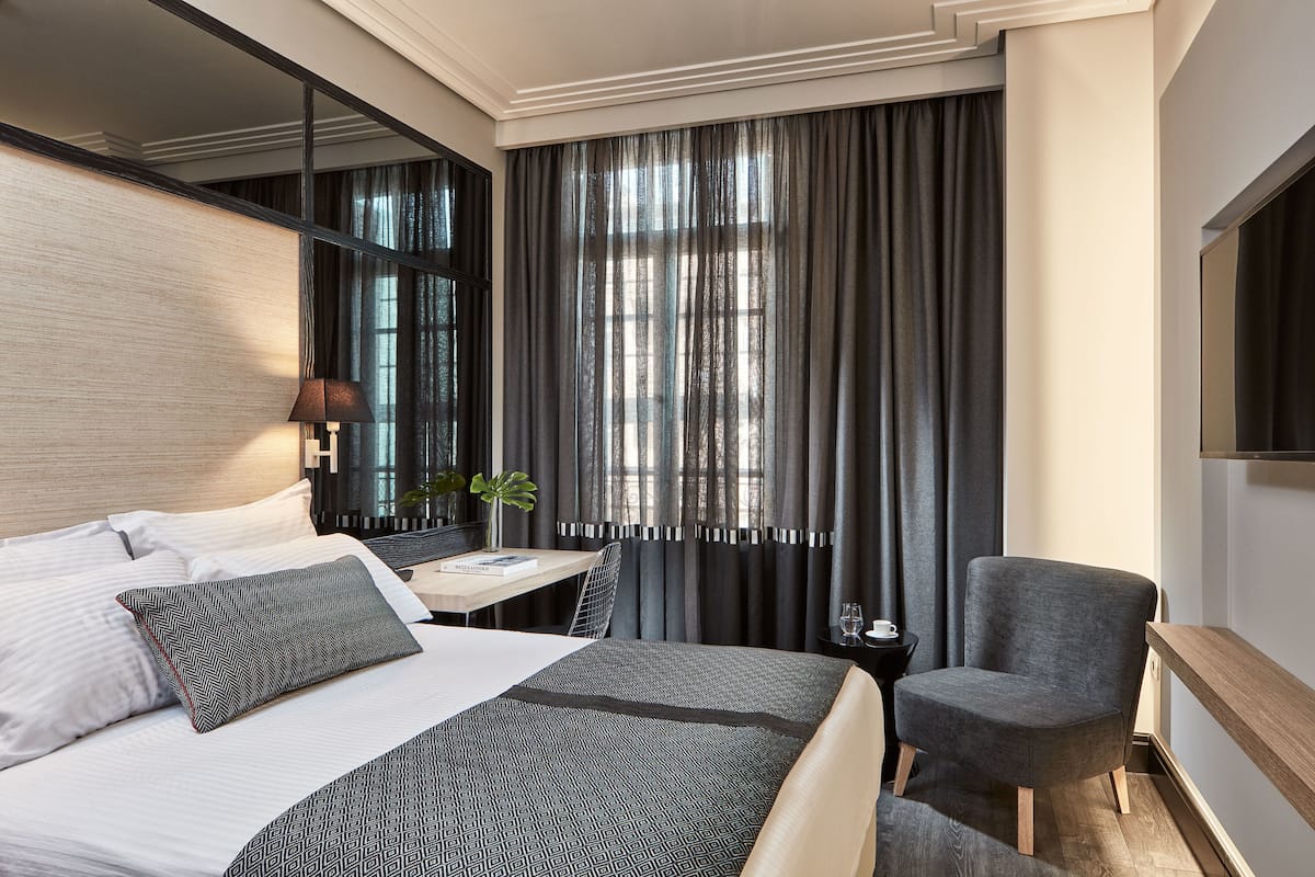 Une chambre d’hôtel avec un grand lit, un bureau, une chaise et un téléviseur.