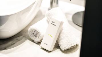 A bathroom sink with a mirror, a towel, and a hotel amenities card.