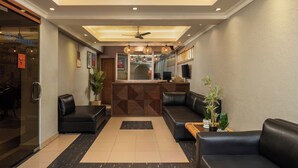 Et hotel lobby med reception, siddepladser og en loftsvift.