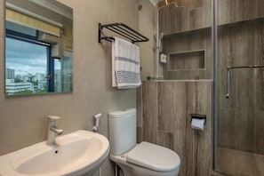 A bathroom with a sink, toilet, and glass shower enclosure. - Hotel Raha Tower  (Dar es Salaam)