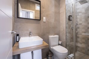 A bathroom with a white sink, toilet, and glass-enclosed shower. - Apartamentos Soho Boutique Museo (Málaga)