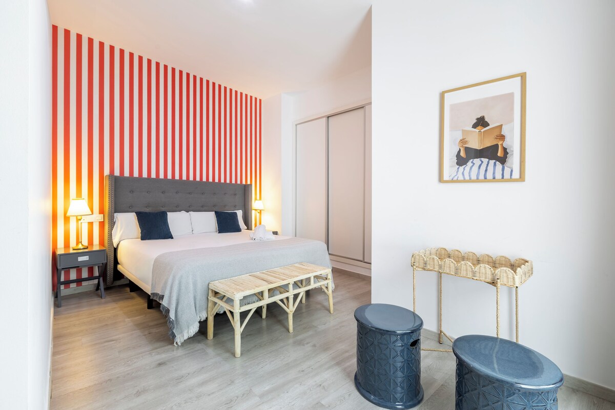 A bedroom with a bed, bedside tables, a bench, a wall-mounted basket, and a framed picture.