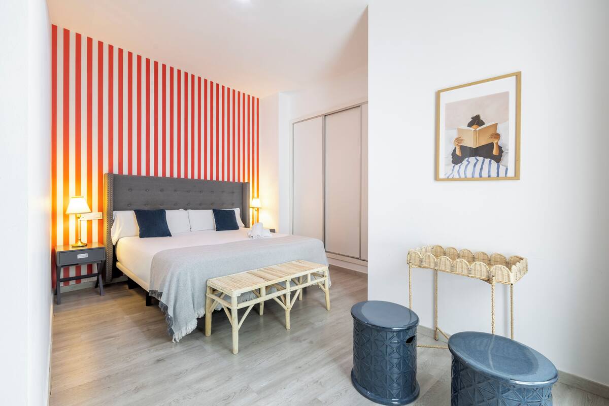 A bedroom with a bed, bedside tables, a bench, a wall-mounted basket, and a framed picture.