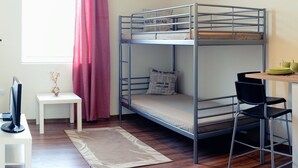 Een slaapkamer met stapelbed, bureau, stoel en hanglamp.
