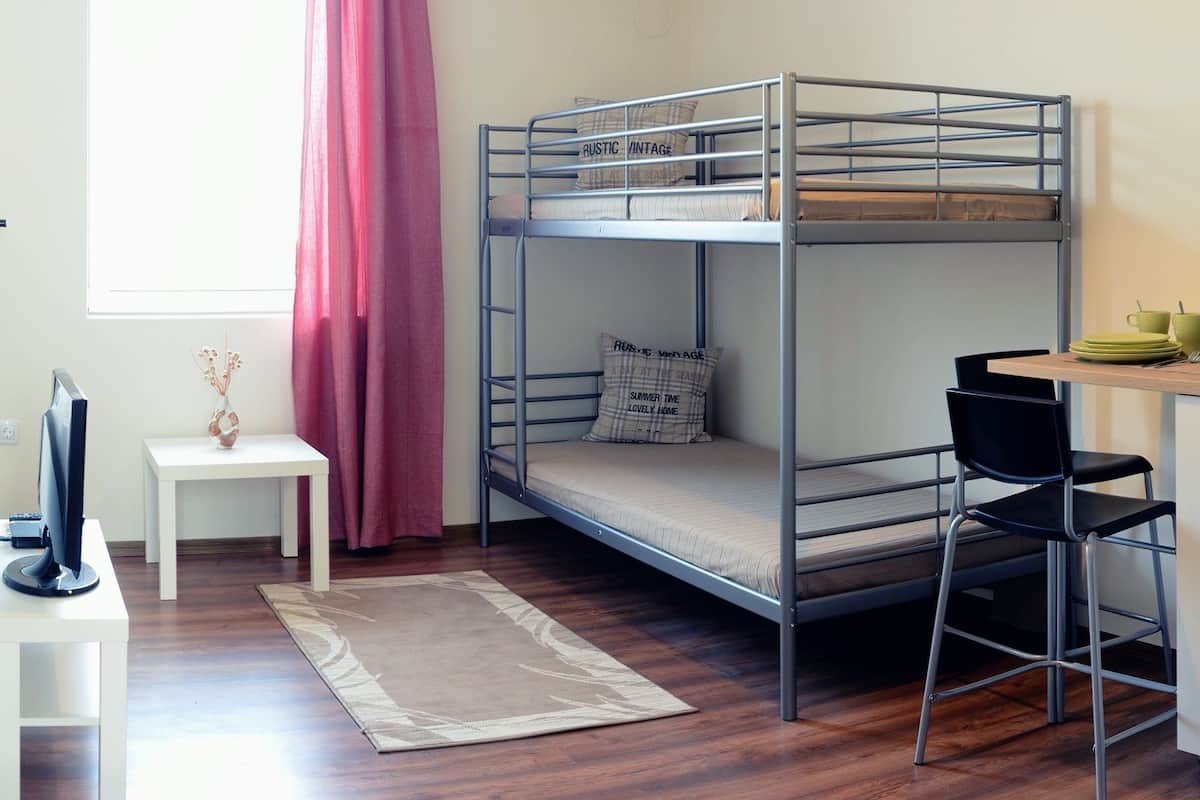 A bunk bed room with a desk, chair, and a hanging light fixture.