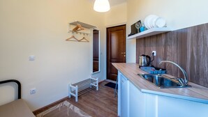 Een compacte keuken met een spoelbak, houten aanrecht en een hangende lamp.