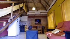A rustic interior with a staircase, kitchen, dining area, and a sofa.