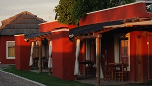 A red building with a thatched roof and a covered outdoor seating area.