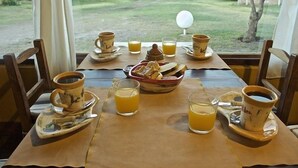 A breakfast setup with coffee and orange juice on a table with a view of a grassy area and buildings in the background.