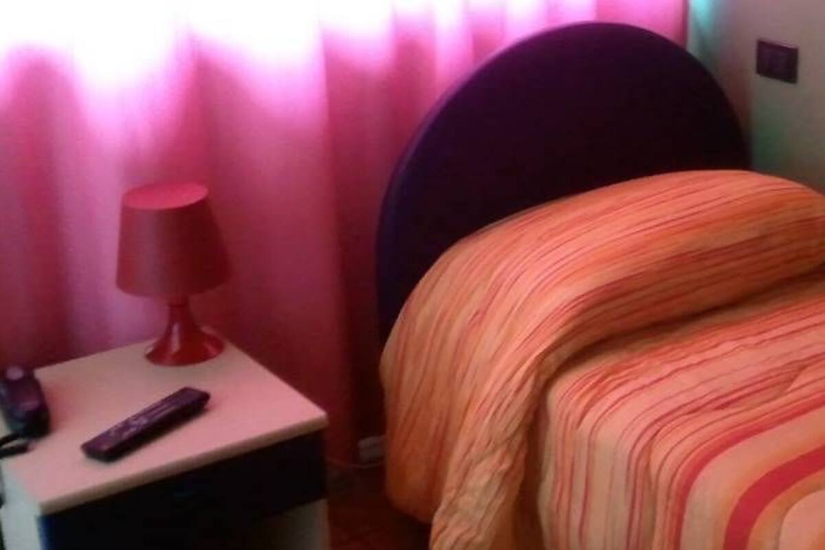 A small, cozy room with a bed, a nightstand, and a lamp.
