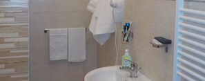A bathroom with a glass shower enclosure, a sink with a handheld mirror, and a towel rack with two white towels. - Hotel Ristorante Euromotel Bari (Bari)