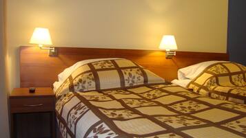 A hotel room with a bed, two bedside lamps, a nightstand, and a wooden headboard.