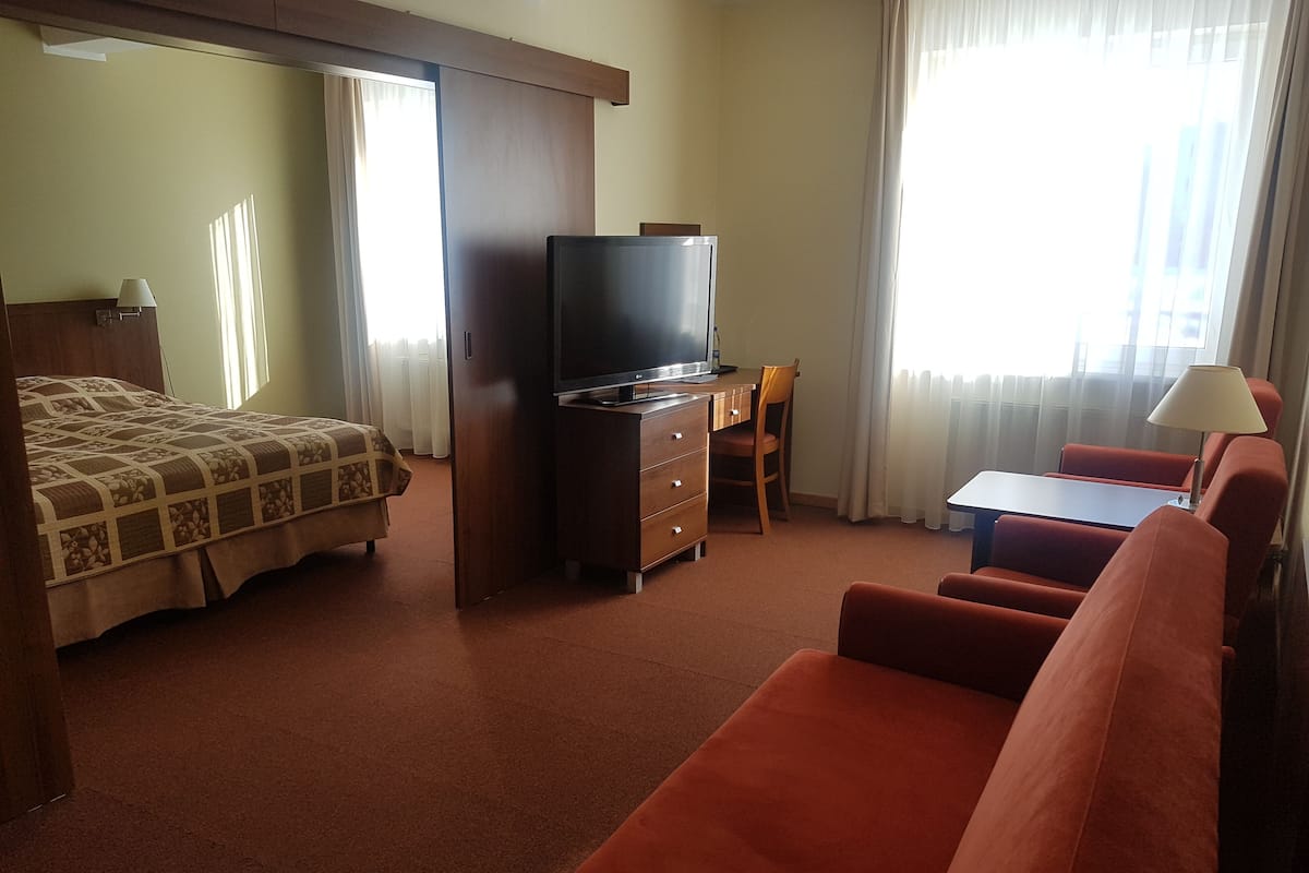 Une chambre d’hôtel avec un lit, une télévision, un bureau et une chaise.