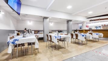Un comedor amplio con varias mesas, sillas y una disposición tipo bufé.