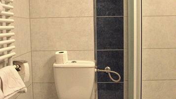 Un baño con inodoro, ducha y toallero.