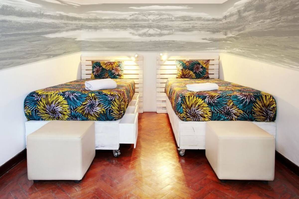 A room with two beds, each with a colorful floral bedspread and white headboards.
