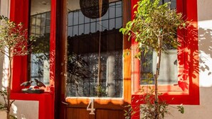 Una porta d'estructura vermella amb el número 4, plantes en testos i un paviment de rajoles.