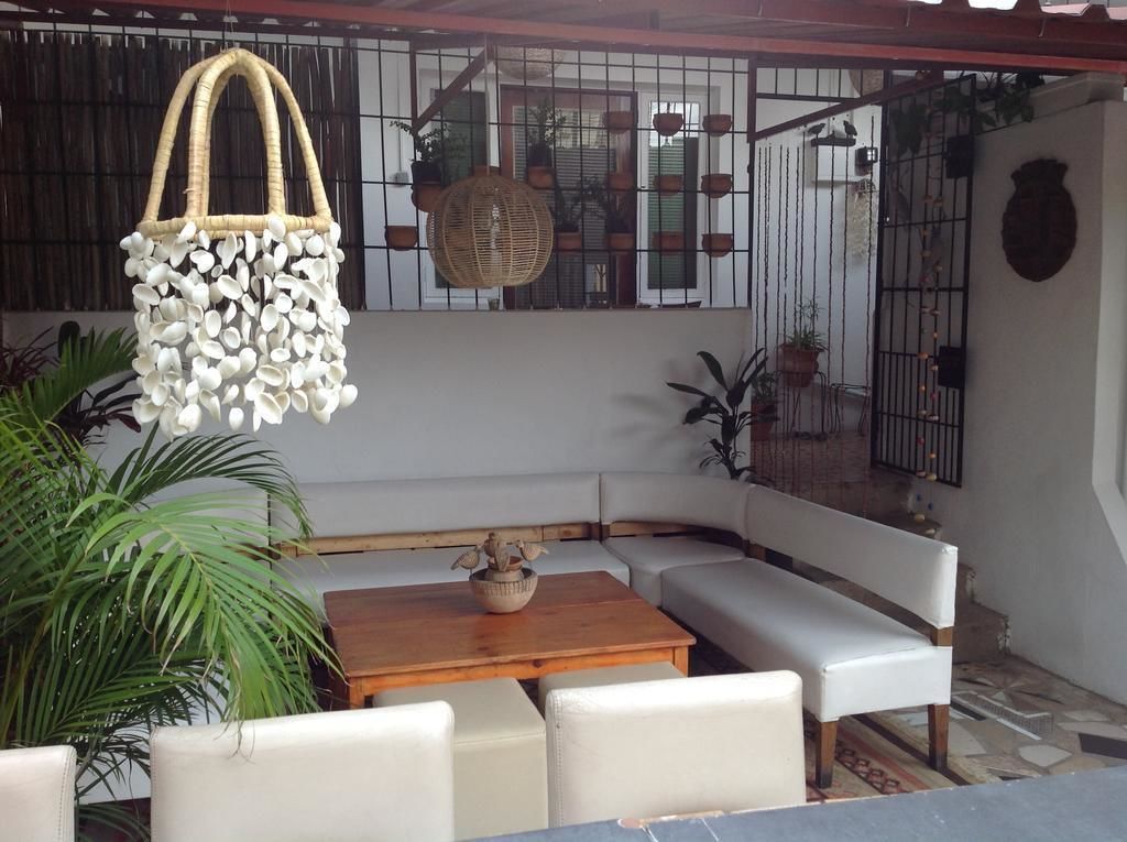 A cozy outdoor seating area with a wooden table, white cushioned benches, and hanging planters.