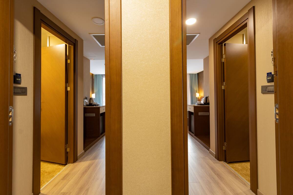 A hotel hallway with wooden doors, a reception desk, and a visible bathroom.