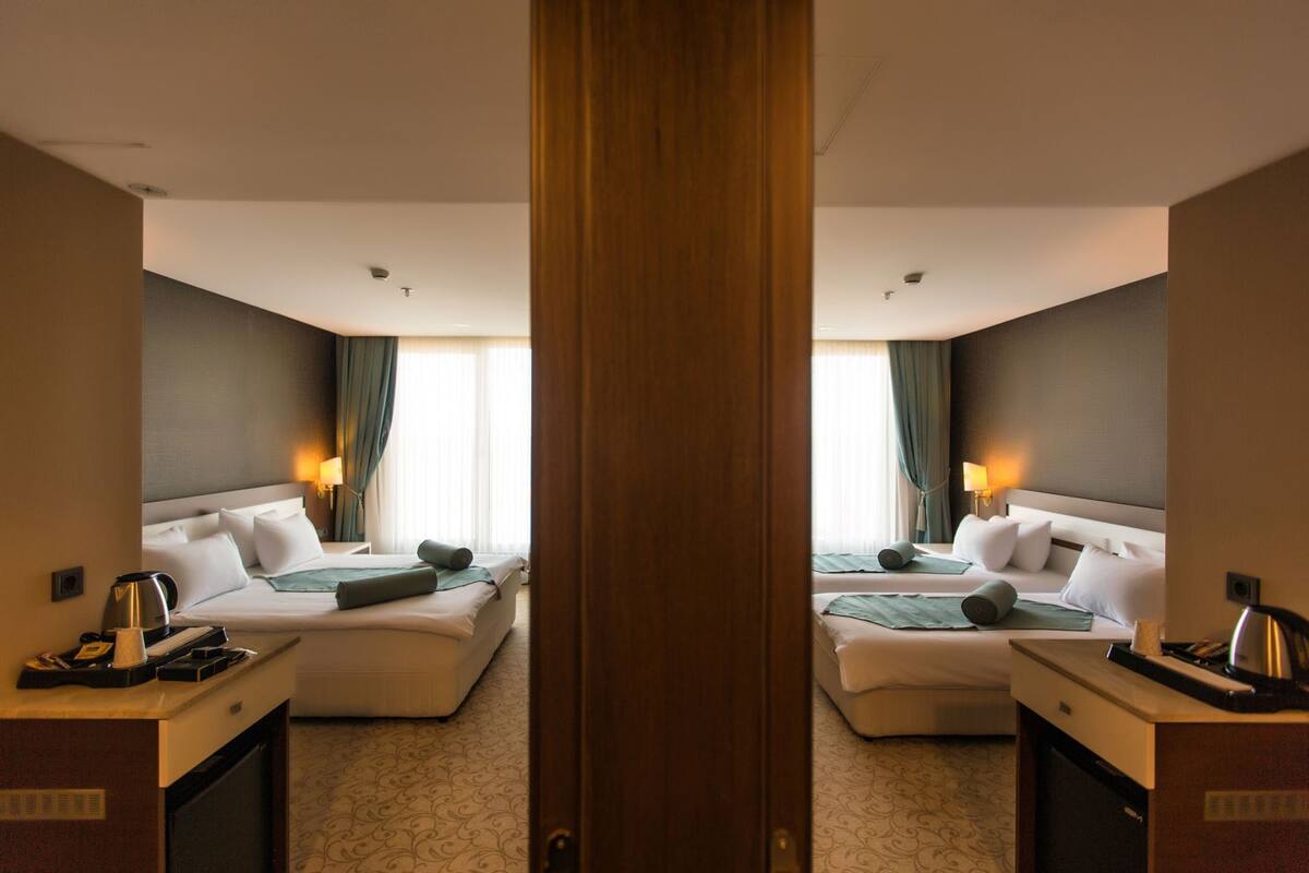 A hotel room with two beds, a desk, a coffee maker, and a lamp.