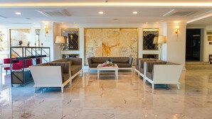 A spacious lobby with a marble floor, two sofas, a coffee table, and a red chair. - Tilya Resort Hotel (Akçaabat)