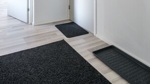 A hallway with two white doors, a black mat at the entrance, and a black mat leading to a room. - Hiisi Homes Lohja (Lohja)