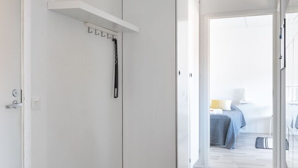 A hallway with a white door, a coat rack, and a black doormat. - Hiisi Homes Lohja (Lohja)