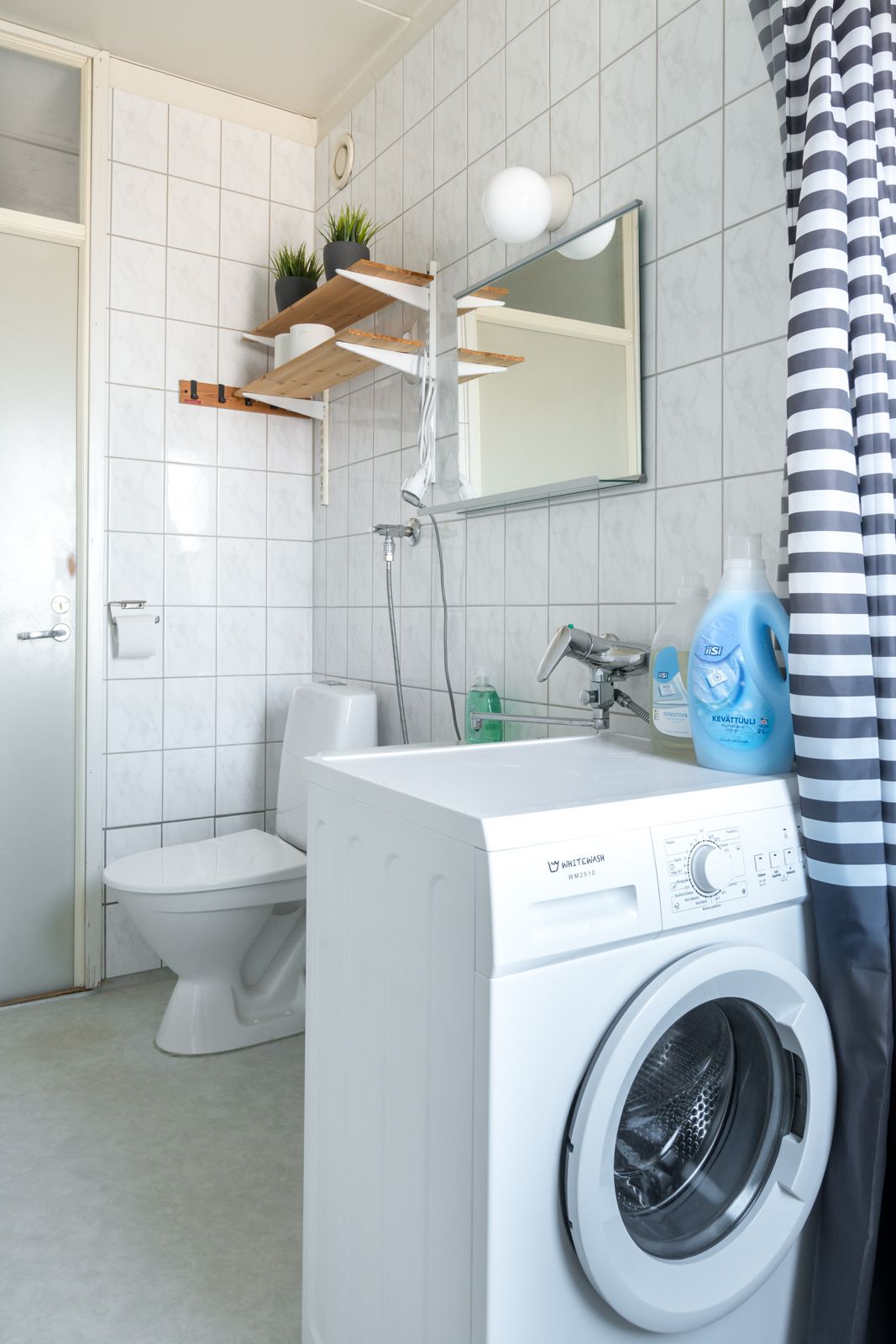 Ein modernes Badezimmer mit Toilette, Waschmaschine und Dusche.