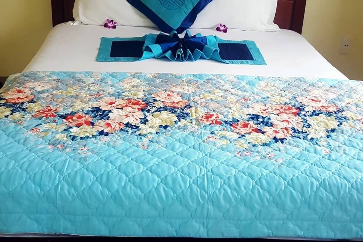 A bed with a floral quilt, a decorative pillow, and a blue bow.