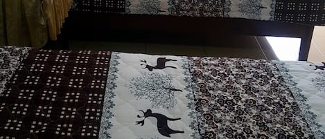 Une chambre avec un lit, une petite table et un téléviseur fixé au mur.