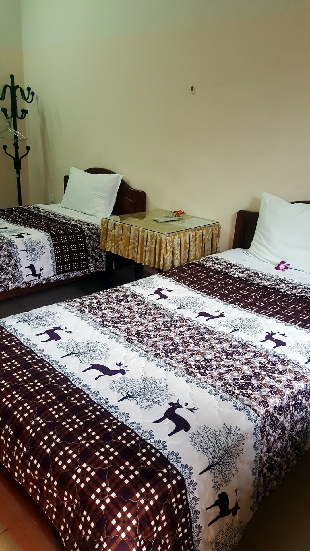 A room with two beds, each with patterned bedding and a table between them.