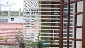 A balcony with a potted plant, a wooden door, and a white railing. - Phong Lan Guesthouse (Hue)