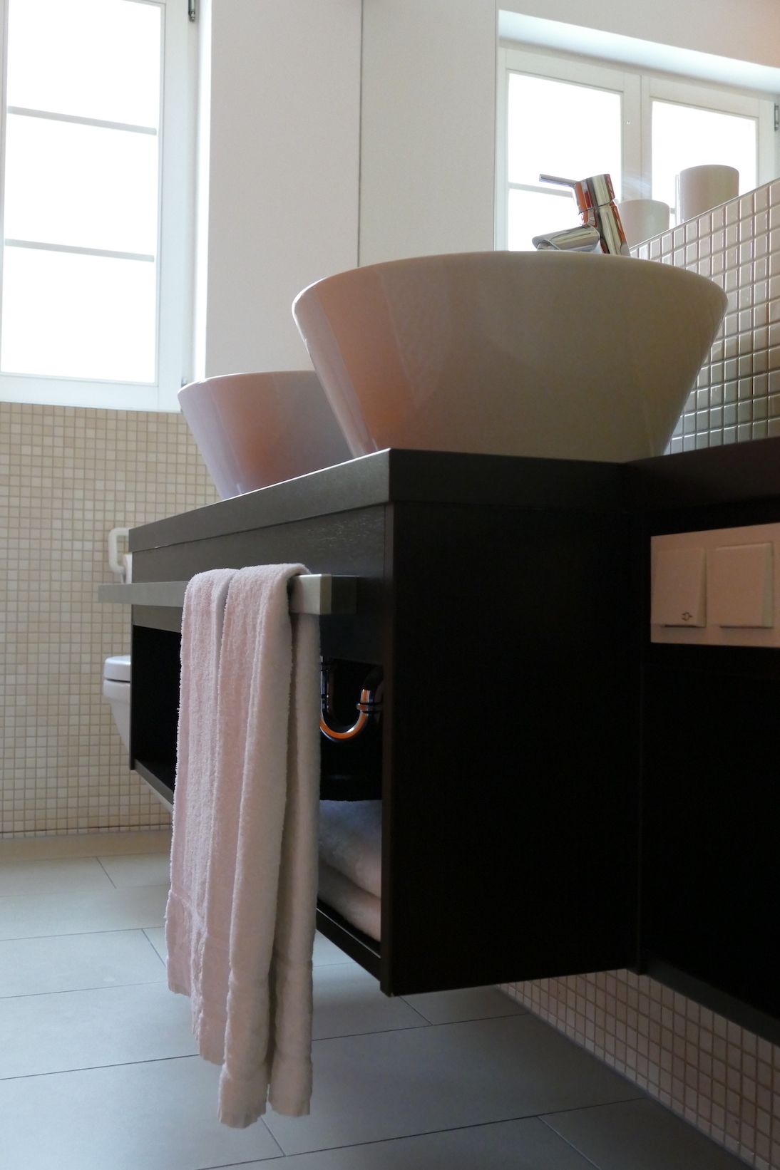 A modern bathroom with a large white sink, a black countertop, and a white towel hanging on a rack.