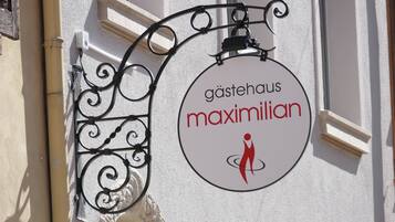 Un letrero circular con el texto "gästhaus maximilian" y la figura de una persona.