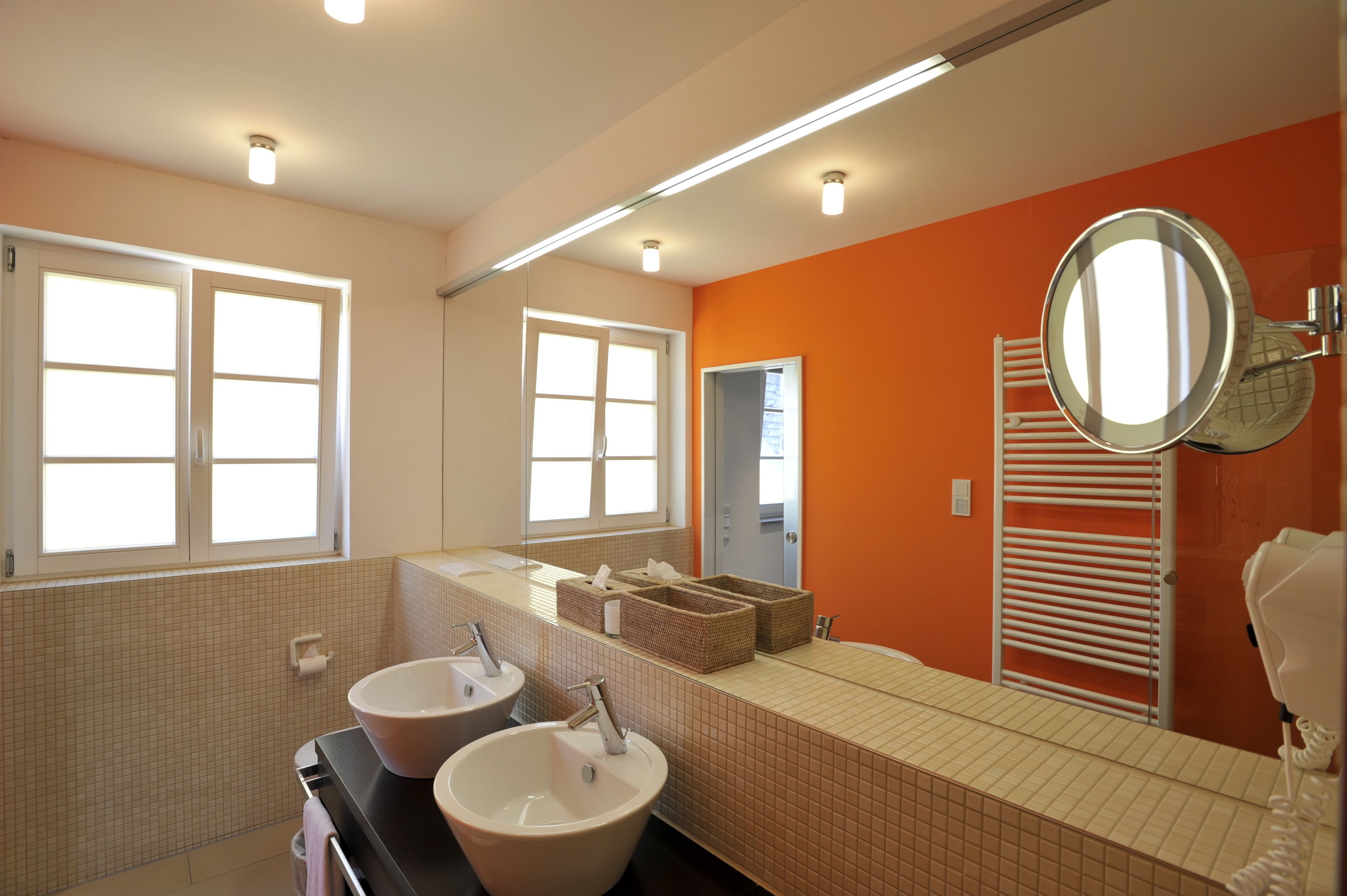 A bathroom with two sinks, a large mirror, and a towel rack.