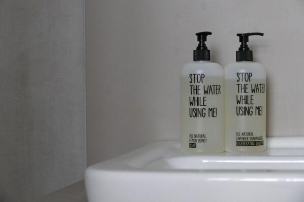 Two bottles of soap on a white sink.