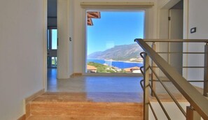 Ein Flur, der zu einem Balkon mit Blick auf eine Küstenlandschaft führt.