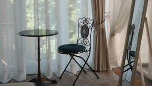 Una habitación con una mesa redonda, una silla, un espejo y cortinas translúcidas.