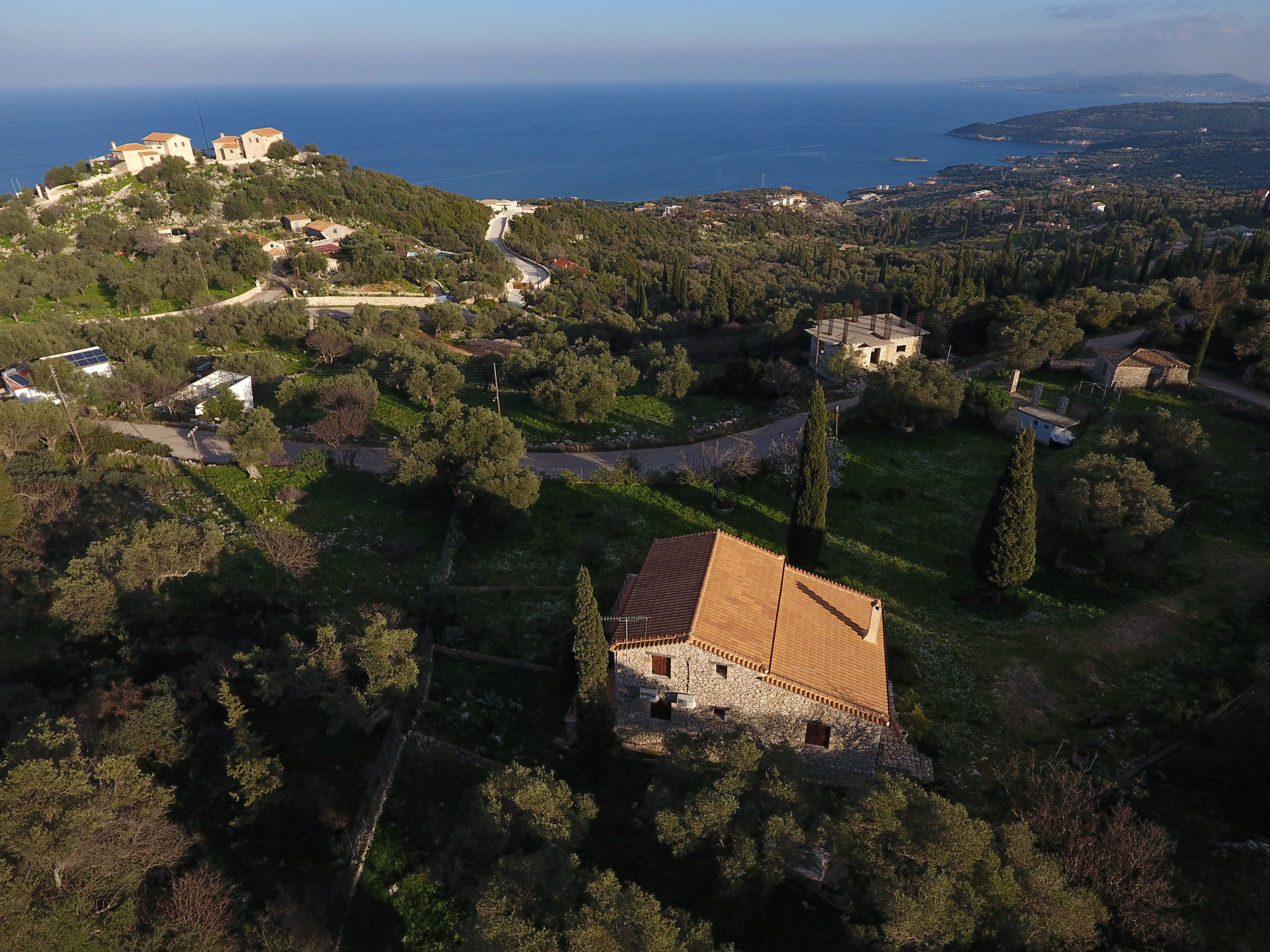 An aerial view of a coastal village with traditional stone buildings, a prominent castle-like structure, and a clear view of the sea.