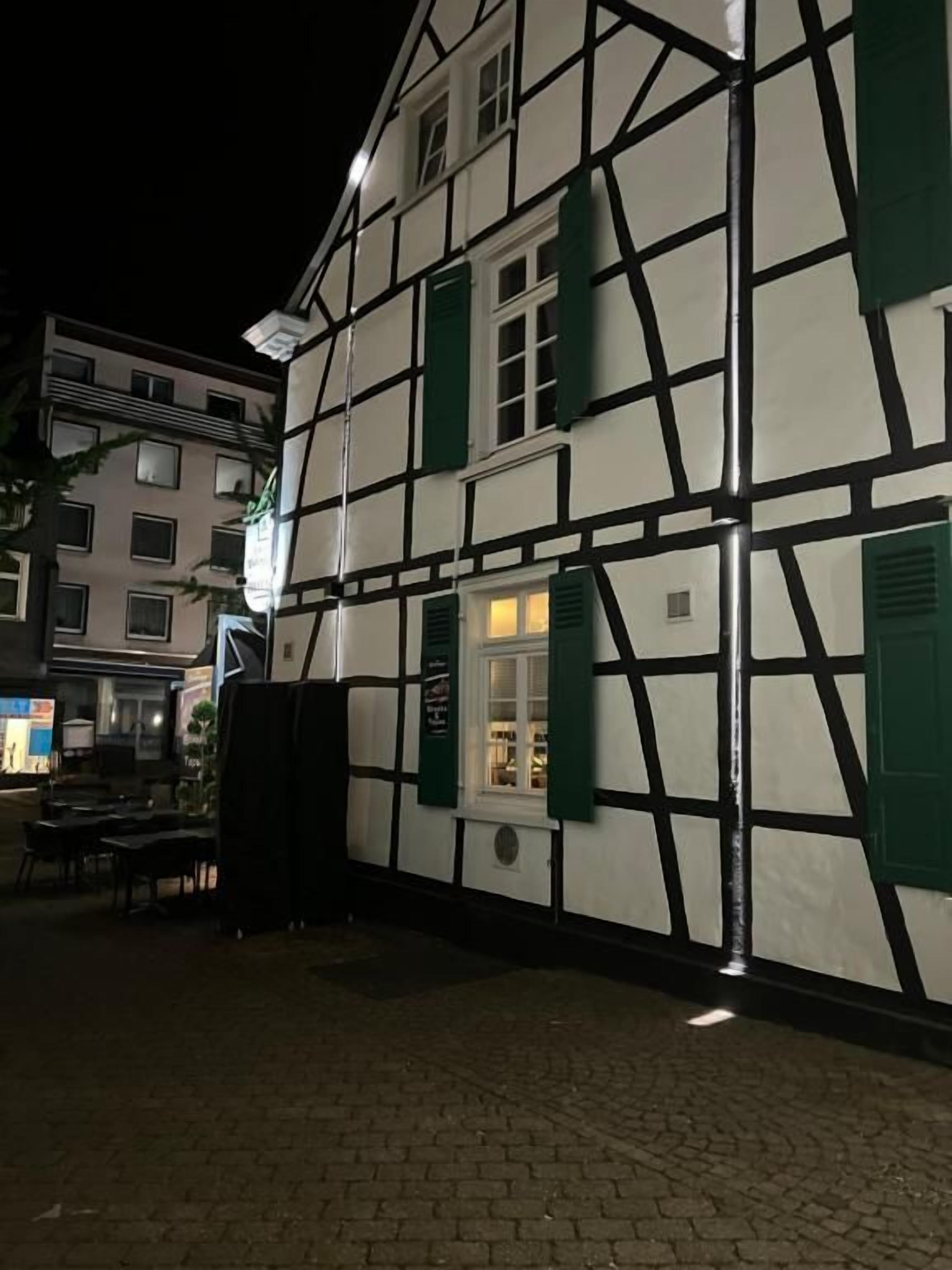 A traditional half-timbered building with a brick ground floor and a second floor with visible windows and shutters.