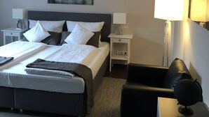 Una habitación de hotel con cama, mesitas de noche, una silla y un escritorio.