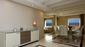Un hotel moderno con un escritorio de vidrio, sillas blancas, un sofá y vista al océano.
