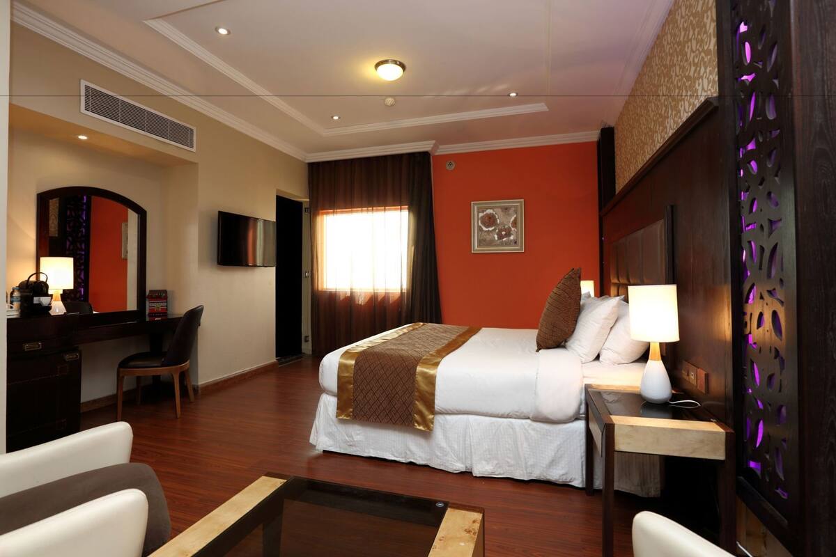 A hotel room with a bed, desk, chair, and a television.
