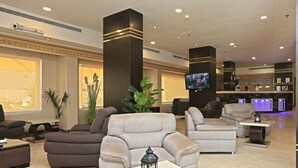 Un lobby moderno con sofás, un televisor y plantas decorativas.