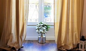 A window with gold curtains, a vase with white flowers, and a metal railing. - Coliseum Suite (Rome)
