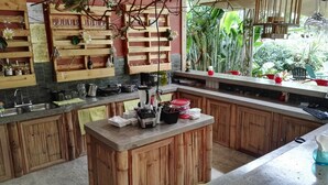 Una cocina con armarios de madera, una isla central con licuadora y una estantería para vinos colgante.