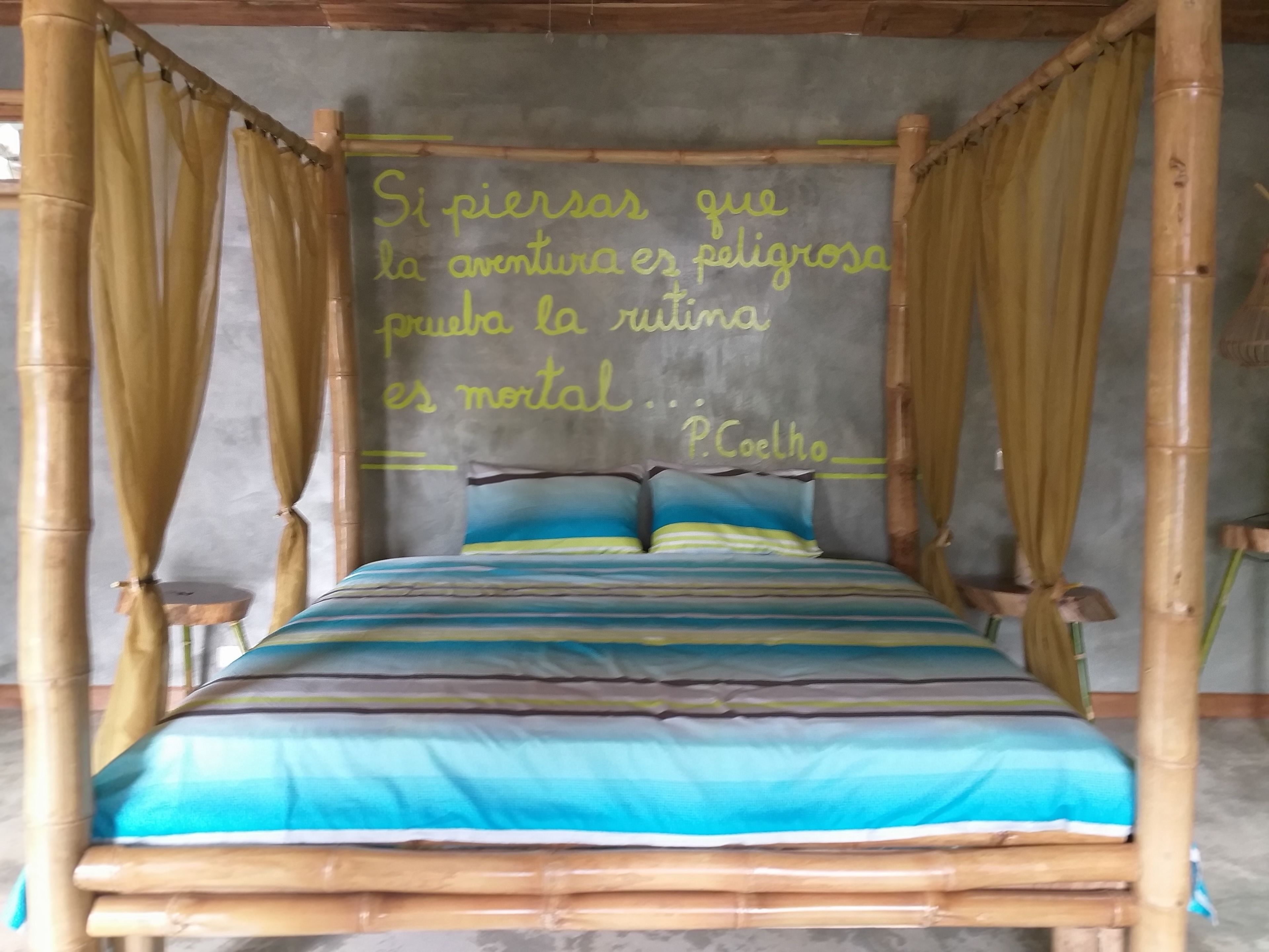Una cama con estructura de bambú y una pared con una cita en español.