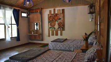 A room with two beds, a wooden ceiling, a painting of flowers, and a small shelf with a vase.