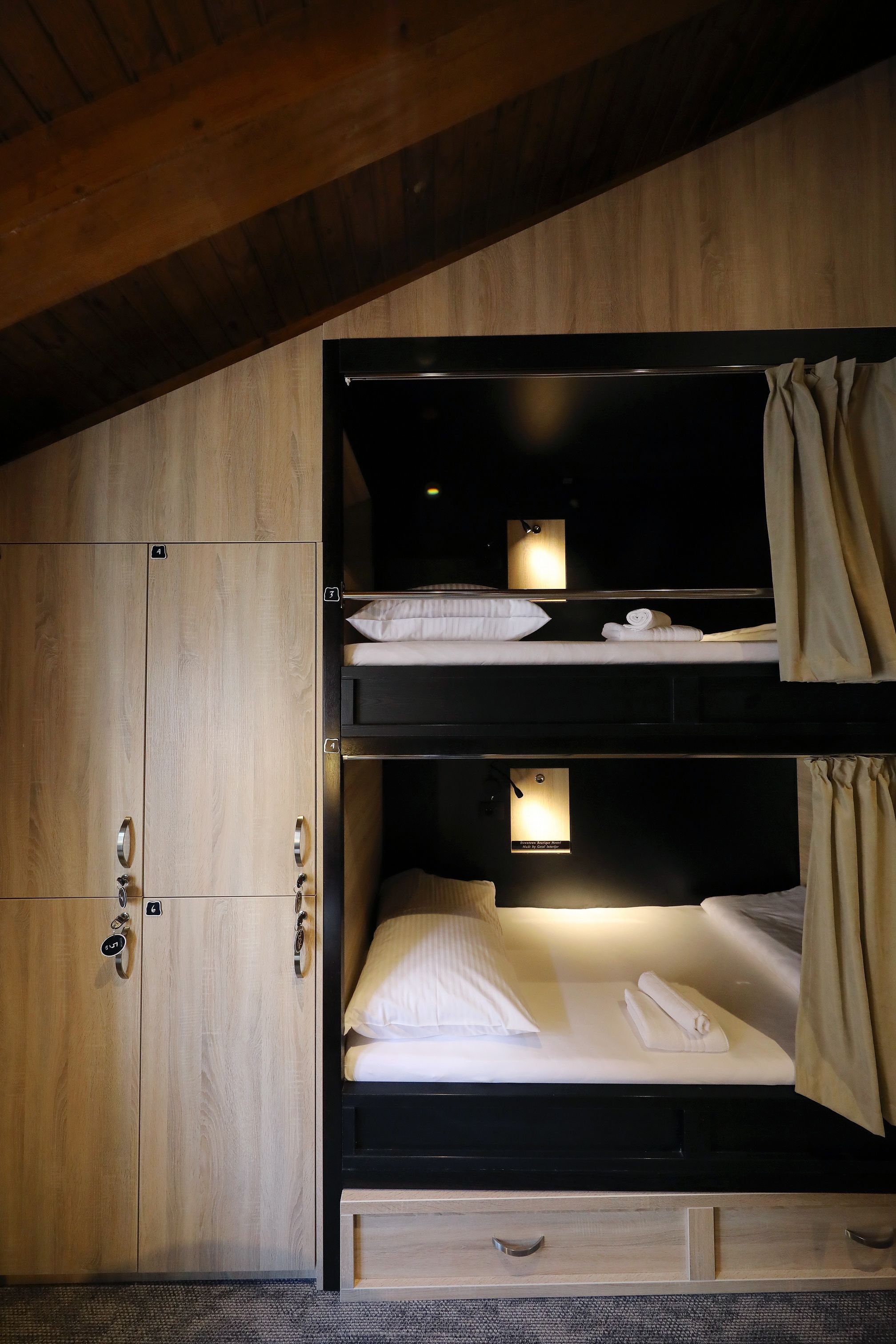 A bunk bed with a wooden wardrobe and a small desk drawer.